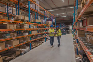 twee-magazijnmedewerkers-die-door-het-distributie- en opslagterrein-lopen-en-over-de-logistieke-organisatie-praten 2.0-01